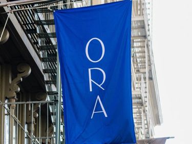 Blue banner hanging in front of building reads ORA
