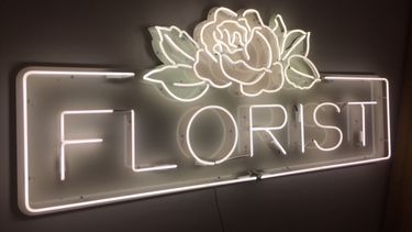 White neon lettering spells 'Florist' with floral design